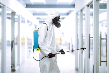 Disinfecting of office to prevent COVID-19, Man in protective hazmat suit with  with spray...
