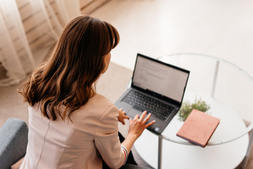 View from the back of businesswoman with laptop writes a letter working at home
