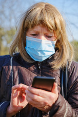 Caucasian elderly woman wears mask for protect coronavirus outbreak and use smartphone to talk with her family