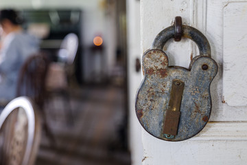 Selected focus and close up view at old rusty vintage retro design of lock hang on white wooden...