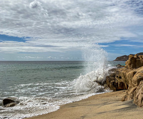 Wave crashes at a rock on a shore