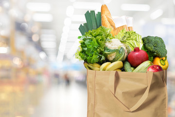 Eco friendly reusable shopping bag filled with bread, fruits and vegetables on a supermarket...