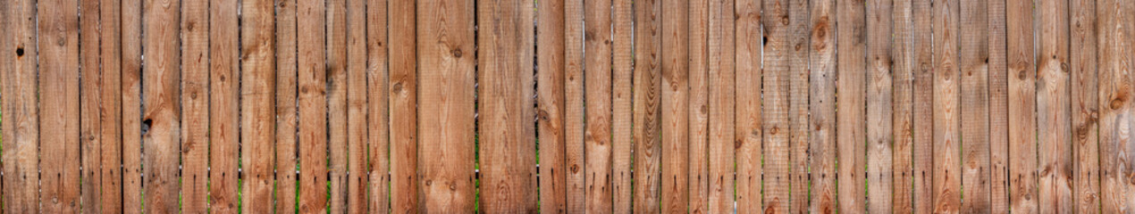 Texture of a wide wooden fence. Old rustic fence made of planks.