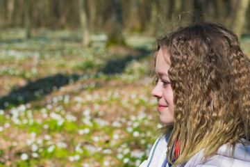 A young girl in the forest in a clearing with flowers