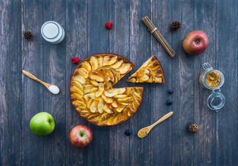 Homemade apple pie surrounded by ingredients on a old wooden surface. Top view. Dessert concept.