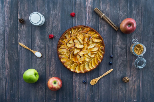 Homemade apple pie surrounded by ingredients on a old wooden surface. Top view Dessert concept.