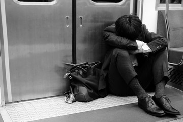 電車のドアの前でうずくまるサラリーマン