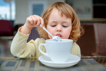 Adorable 2 years old little girl drinking mug coffee tea hot drink in outdoor cafe. Healthy eating for kids. Travel with young children.