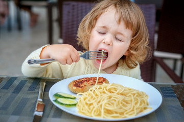 Adorable 2 years old little girl eating pasta and cutlet in a cafe during her voyage, food and drink. Healthy eating for kids. Travel with young children - 339333644