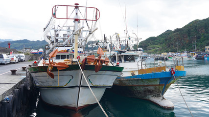 Asian fishing boats anchored in port. Taiwanese multi-colored fishing trawler moored in bay on...