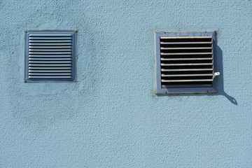 square metal ventilation grate in a blue wall, close view, delivers fresh air and cools