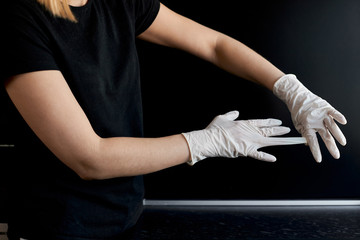 Fototapeta na wymiar Close-up hands of a girl in a black t-short shows how to remove silicone gloves from hands