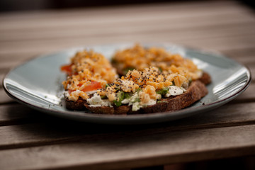 Avocado toasts with scrambled eggs, feta cheese and tomatoes