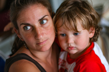 Mother and young son look off in a somber and serious manner