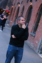 Young man with hand on chin thinking in historic urban setting