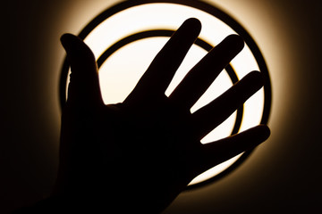 Shadow theatre. Human palm opposite the light of an electric lamp. Theme of childhood and fairy tale in night.