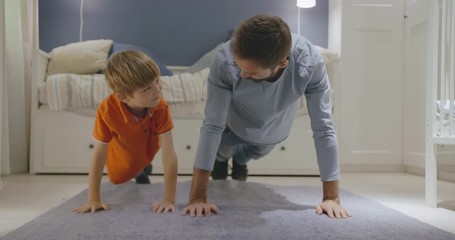 Happy father and little son doing exercises staying at home