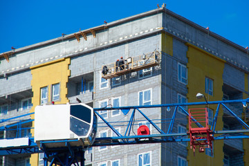 construction crane with workers building a tall house in the city