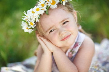 Little girl in nature with a wreath of flowers on her head.