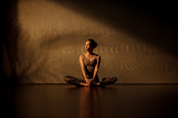 Young Asian woman practicing yoga in moody studio during golden hour