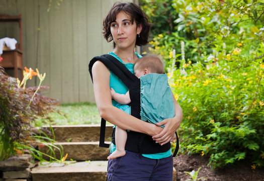 Mom taking baby for a stroll around her home while baby fusses in baby carrier 