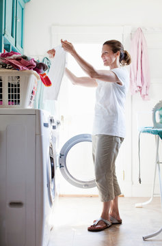 Woman keeping things clean, doing laundry at home, folding clothes from a hamper