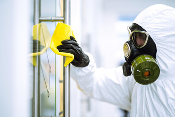 Cleaning and disinfection of office to prevent COVID-19, Man in protective hazmat suit washes office furniture to preventing the spread of coronavirus, pandemic in quarantine city.

