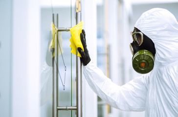 Cleaning and disinfection of office to prevent COVID-19, Man in protective hazmat suit washes...