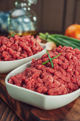 Raw ground beef in closeup with ingredients - ready for cooking