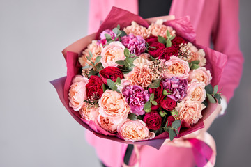 Bright berry color, Beautiful bouquet of mixed flowers in womans hands. the work of the florist at a flower shop. Delivery fresh cut flower. European floral shop.