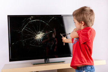 Cute small boy aiming to shattered TV screen with a slingshot.