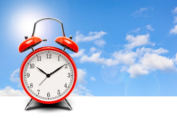 Red alarm clock on blue sky background