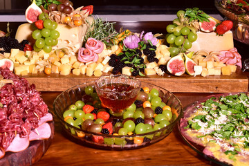 delicious portion with grape figs, strawberries, cheese, ham, raspberries and seasoning served on rustic wooden board with blurs