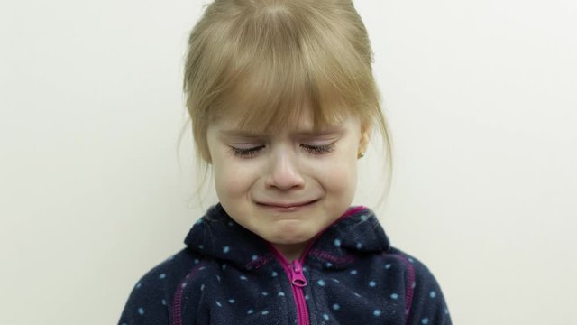 Portrait of little child girl crying with tears down her face. White background