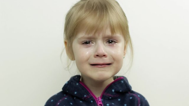 Portrait of little child girl crying with tears down her face. White background