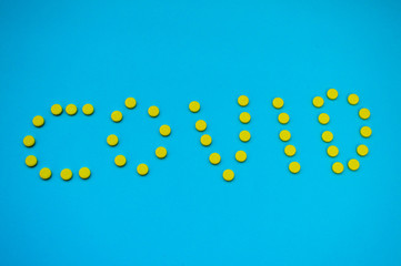 The inscription сovid - 19 made of round yellow medical pharmaceutical tablets from coronavirus...