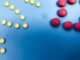 Round multicolored red and yellow medical pharmaceutical medicines for the treatment of diseases killing microbes and viruses pills and vitamins medicines for coronavirus on a blue background