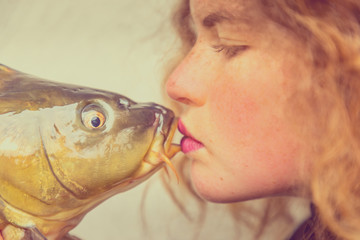 The kiss - Young beautiful woman with curly hair kisses a carp