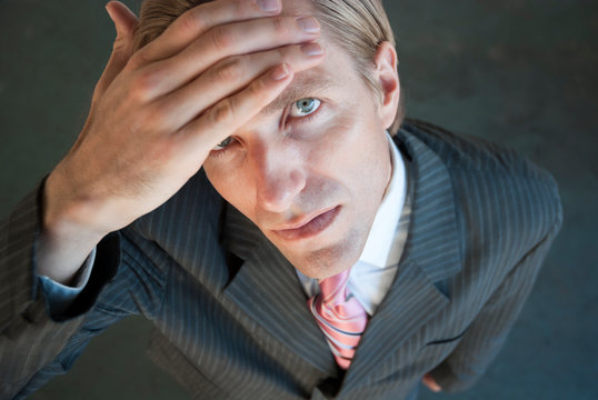 Serious Businessman Wiping Sweat From His Brow Looking Up At The Camera With An Expression Of Relief