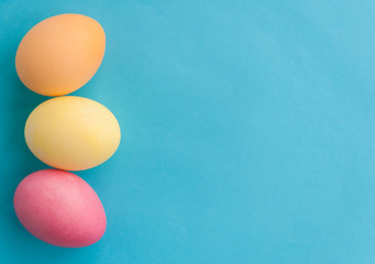 Flat lay flower of colorful eggs on a blue background. Pastel colors, vintage card. Negative space for text