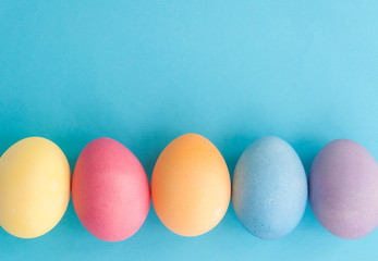 Colorful Easter Eggs in a line on side of a blue background with extra, blank room or space for copy, text, or your words. It's horizontal and perfect for a card or party invite