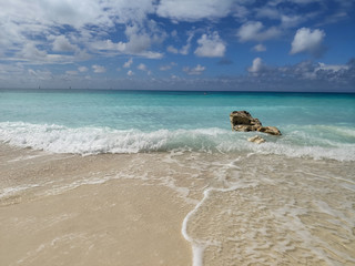 Caribbean beach with turquoise sea and a rock in the foreground