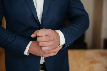 Stylish young man buttoning the cuff links on the sleeves. Style