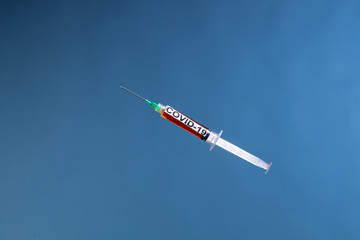 syringe coronavirus vaccine on blue background