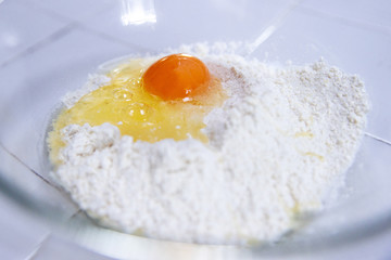 raw egg on pile of flour ingredients for pancake recipe