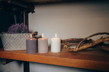 detail of a shelf in a comfortable room with candles, purple flowers