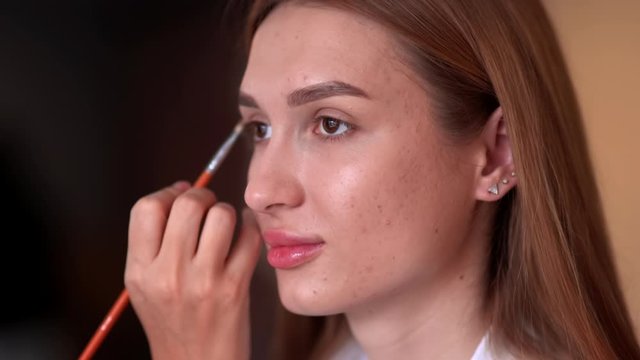 Makeup artist paints the eyes of a girl model