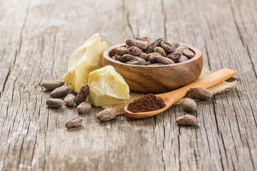 Fototapeta na wymiar Cocoa butter or Cocoa bean solid oil with cacao powder in spoon and raw cocoa beans in wooden bowl on rustic backdrop, healthy natural oil