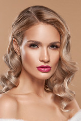 Fototapeta premium Fashion closeup portrait of blonde beautiful woman with glamour make-up and long wavy hair looking at you. Pretty spa female model with perfect fresh clean skin