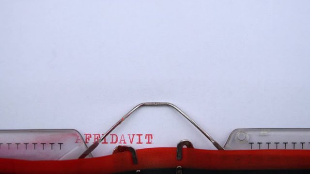 Affidavit - word printed on an old typewriter in red letters, close up. vintage inscription